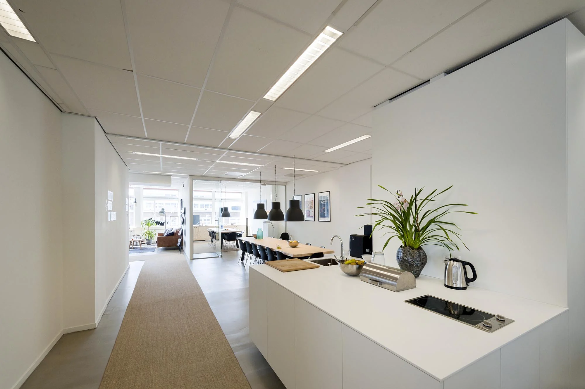 Moderne kantoorruimte aan de Helicopterstraat met open keuken, lange vergadertafel en glazen vergaderruimte.