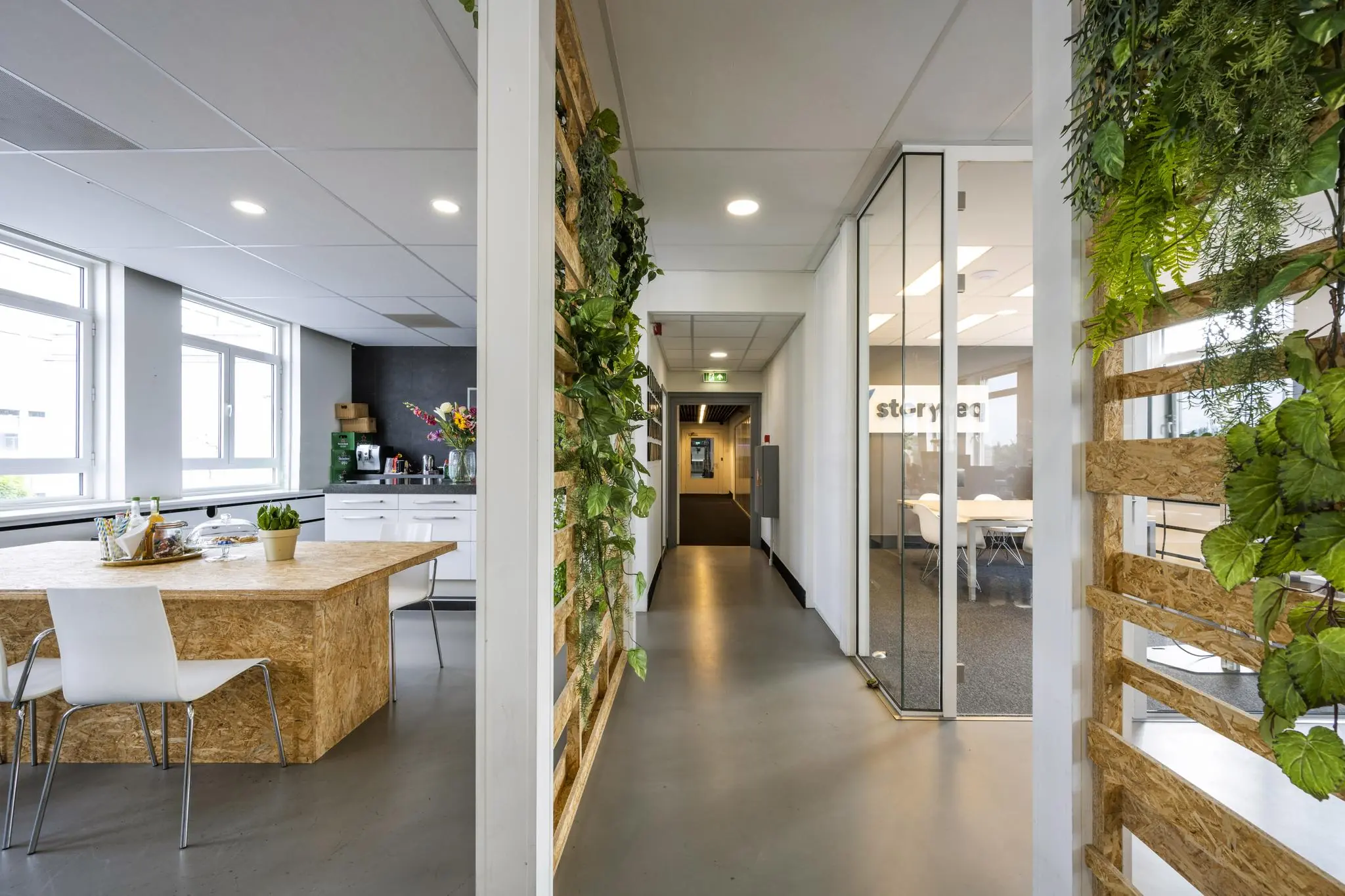 Moderne kantoorruimte aan de Vliegtuigstraat met keuken, vergaderruimte en groene wanddecoratie.