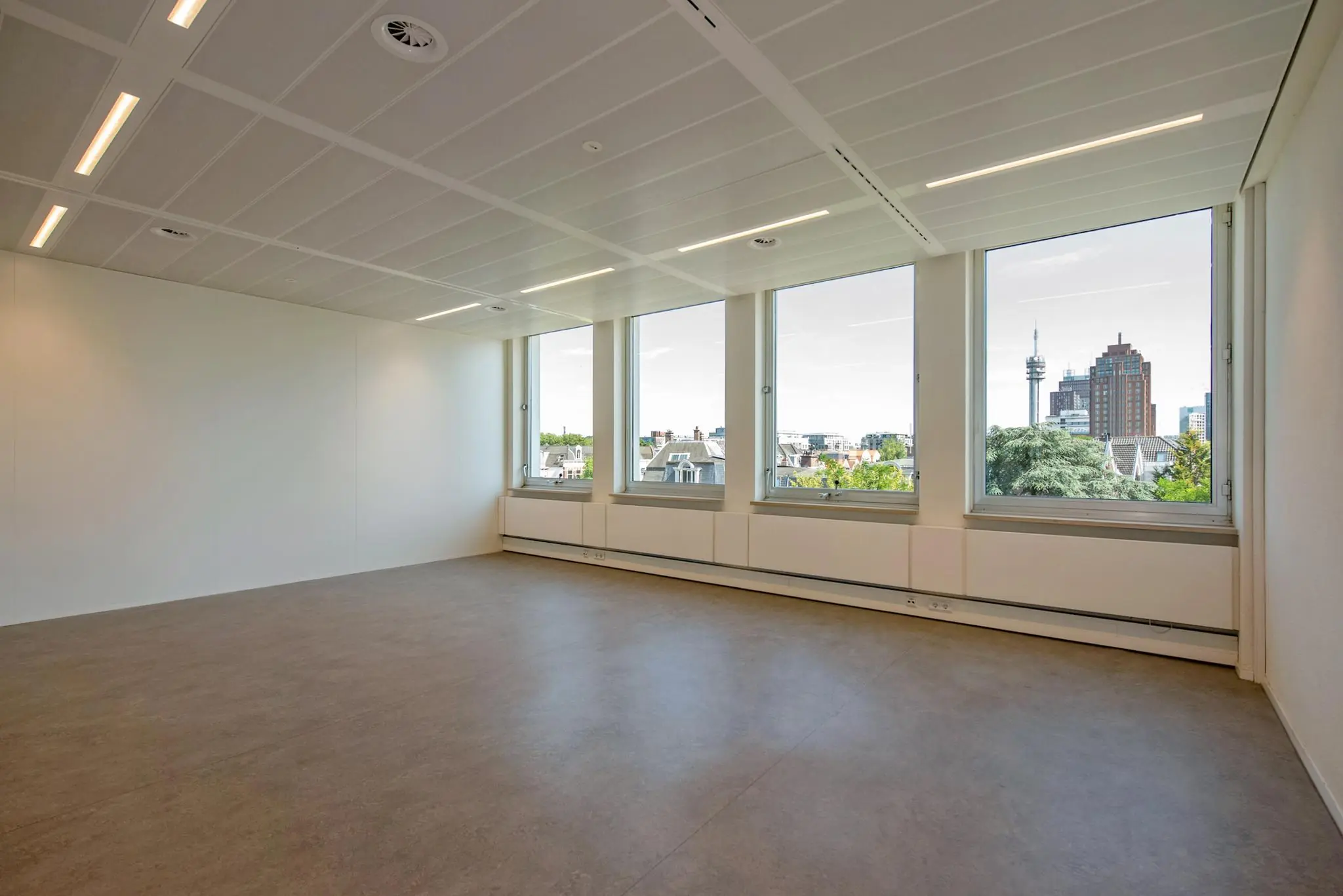Lege, moderne kantoorruimte aan de Bezuidenhoutseweg met grote ramen en uitzicht op de skyline van Den Haag.