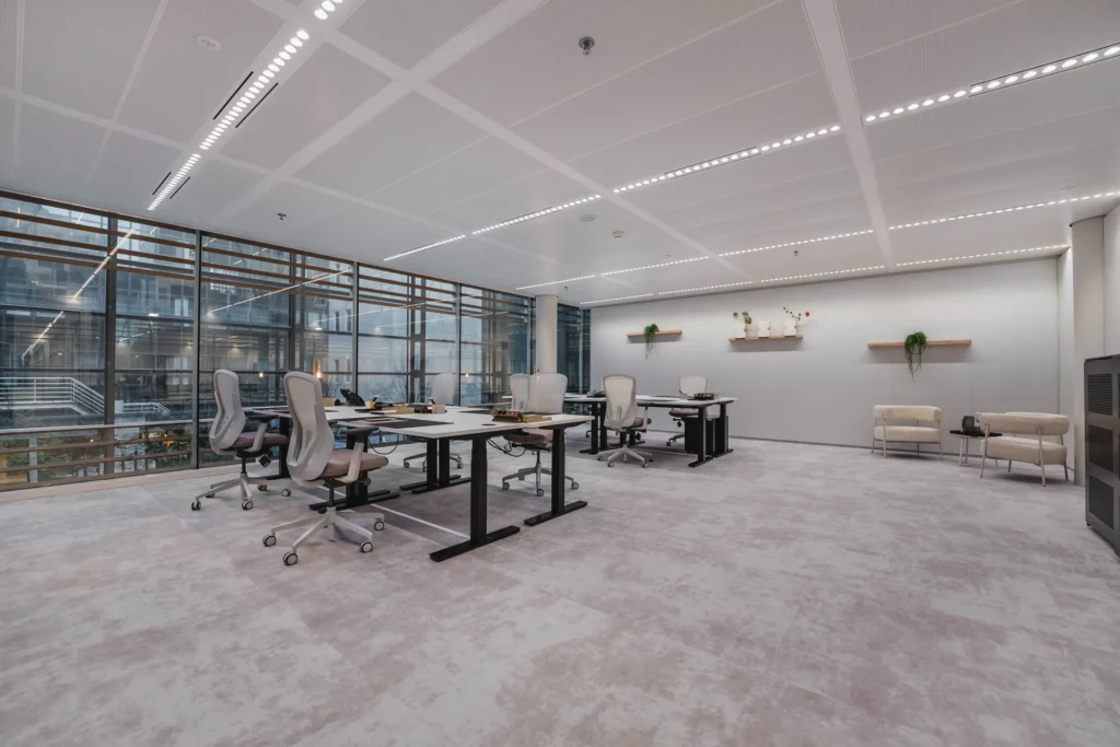 Een moderne kantoorruimte met bureaus, comfortabele stoelen en grote ramen.