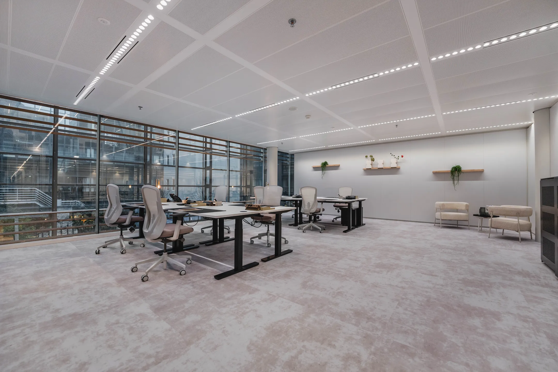 Een moderne kantoorruimte met bureaus, comfortabele stoelen en grote ramen.