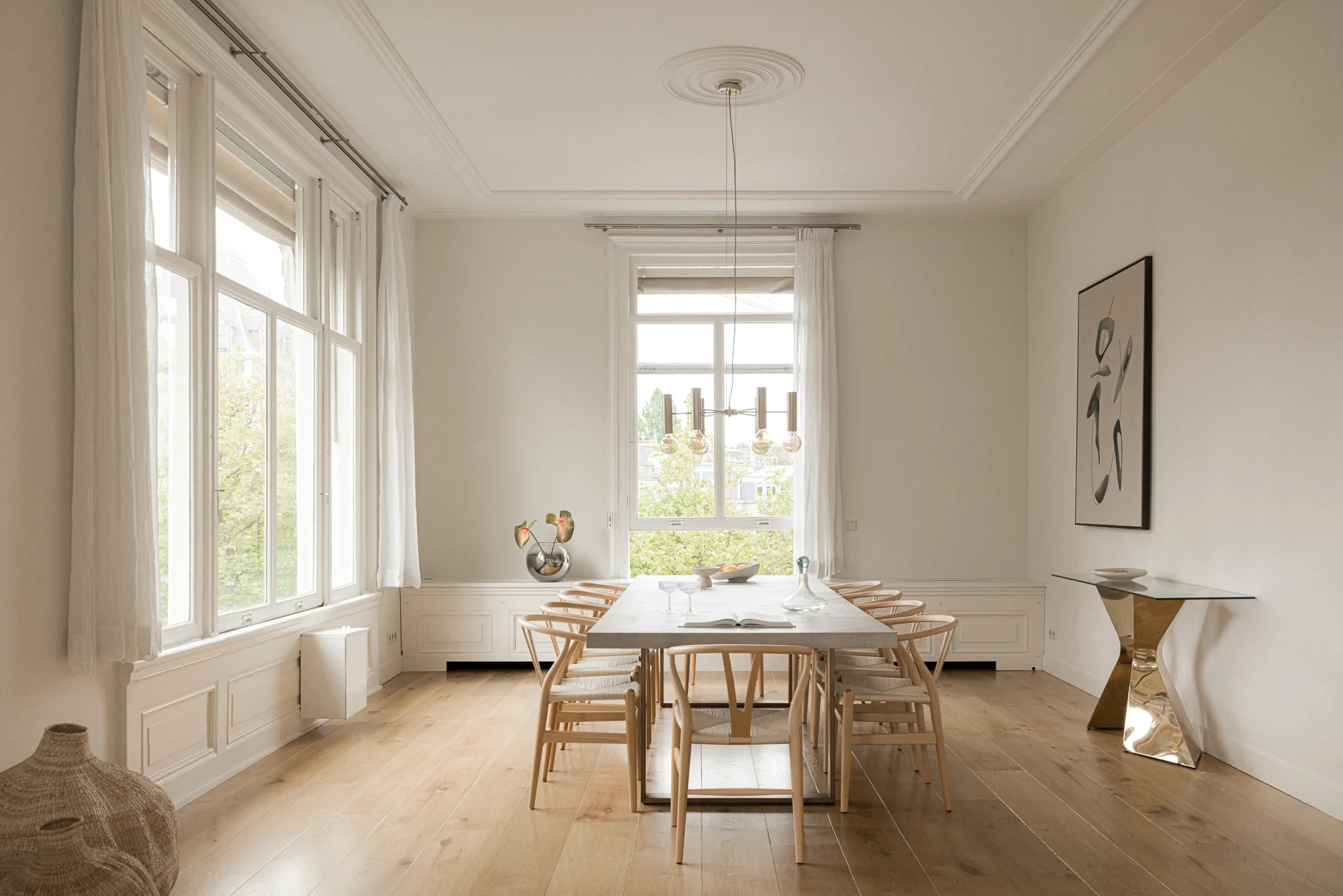 Licht en modern ingerichte eetkamer aan de Weteringschans met houten vloer, minimalistisch meubilair en grote ramen.