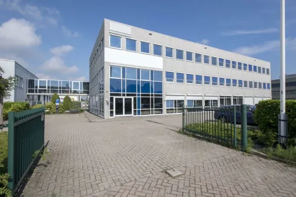 Wit kantoorgebouw met grote ramen en parkeerplaats aan de Witboom in een industriële omgeving.