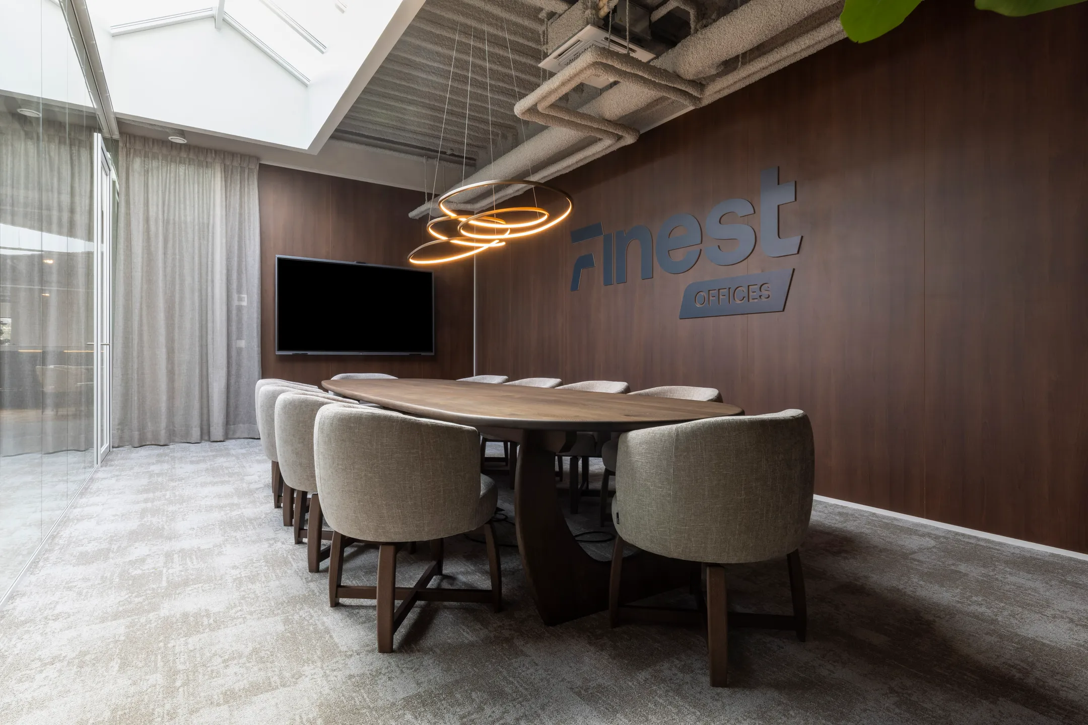 Een moderne vergaderruimte met een lange houten tafel, comfortabele stoelen en een tv aan de muur met het logo "Finest Offices".