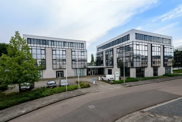 Twee moderne kantoorgebouwen aan de Cypresbaan met grote spiegelramen en een parkeerterrein ervoor.