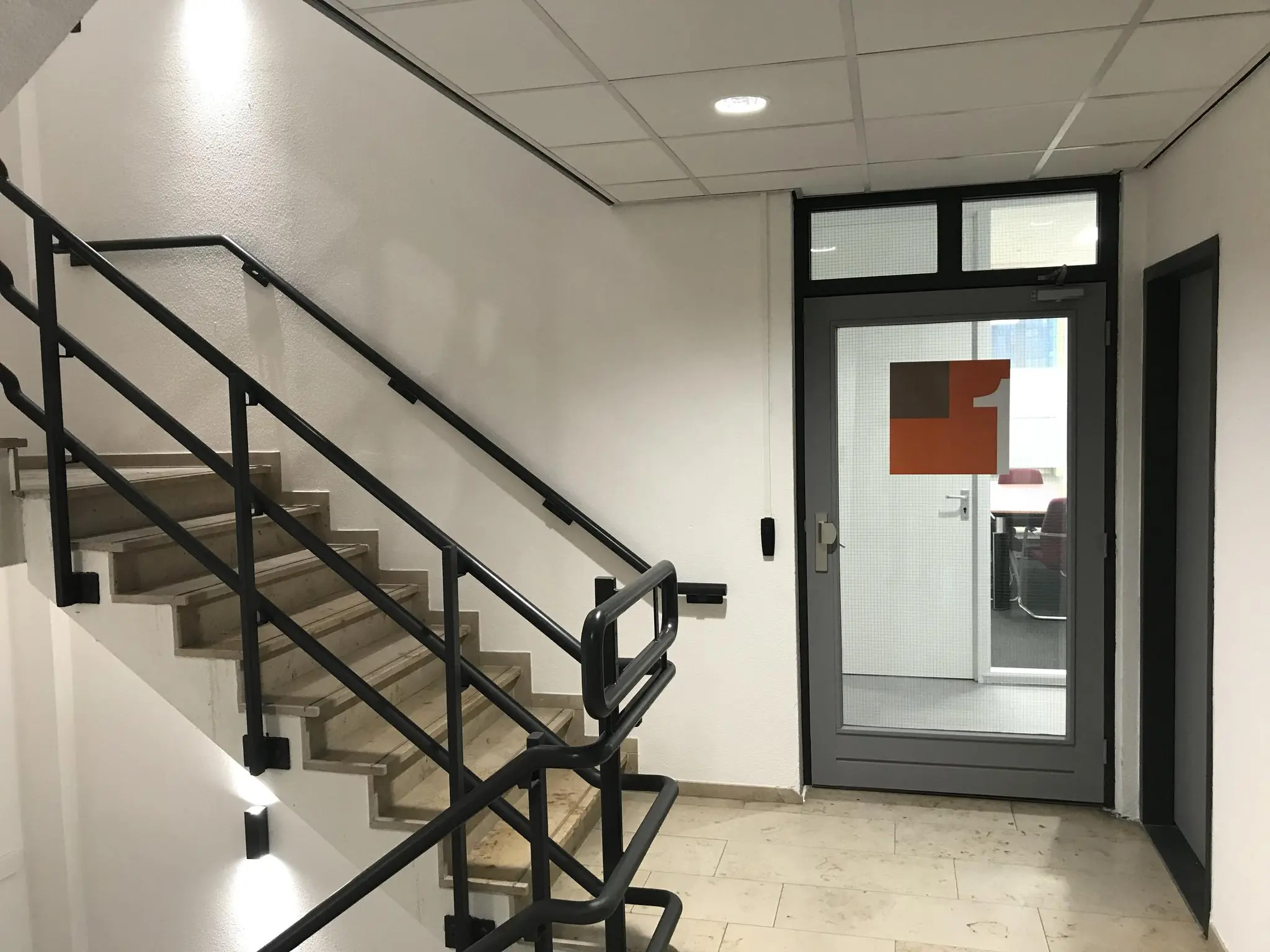 Trapopgang en glazen deur met rood logo in een kantoorpand aan de Cypresbaan.