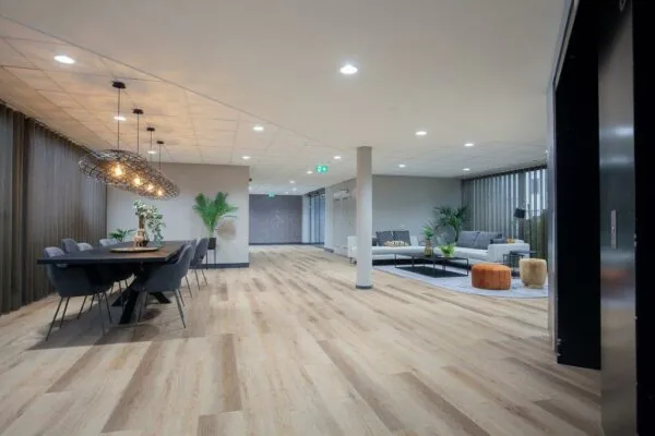 Moderne, sfeervol ingerichte gemeenschappelijke ruimte aan de Cypresbaan met zithoek, eettafel en houten vloer.