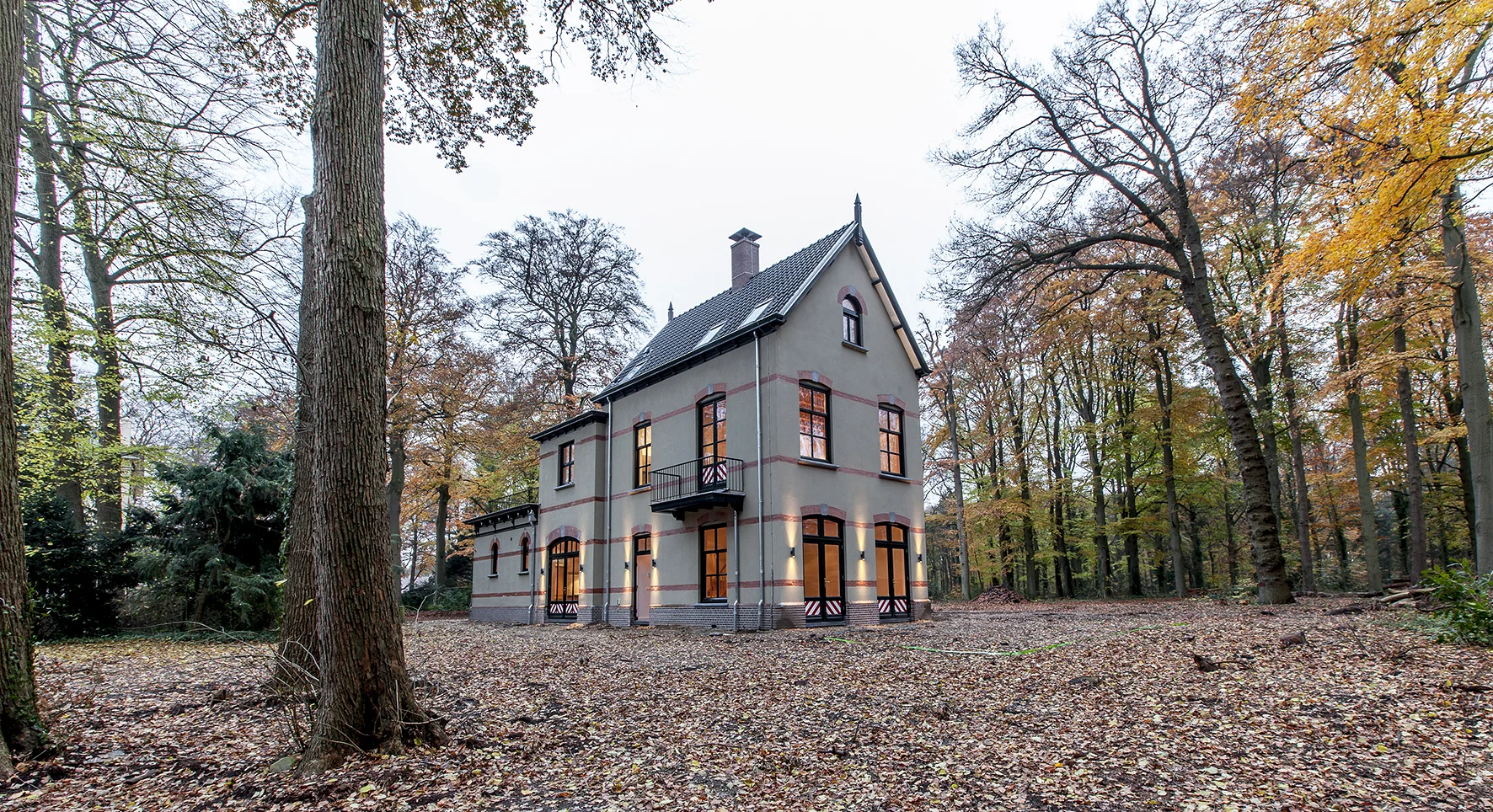 Vrijstaand herenhuis aan de Naarderstraat, omgeven door een herfstachtig bos.
