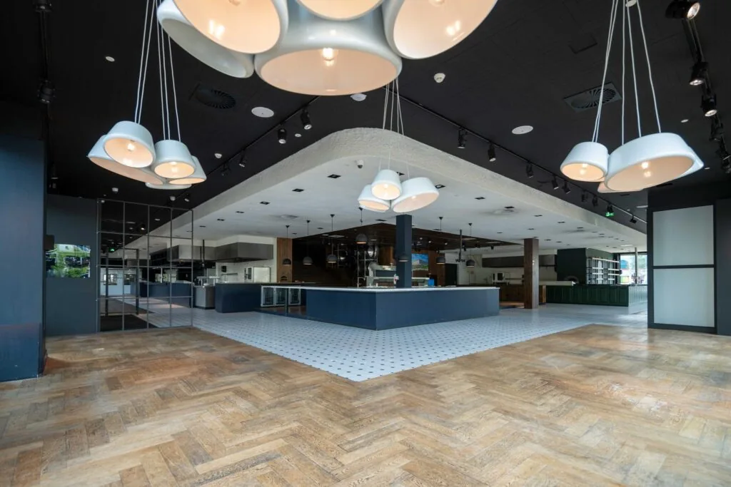 Moderne, ruime horecagelegenheid aan het Stadionplein met open keuken, opvallende verlichting en houten visgraatvloer.