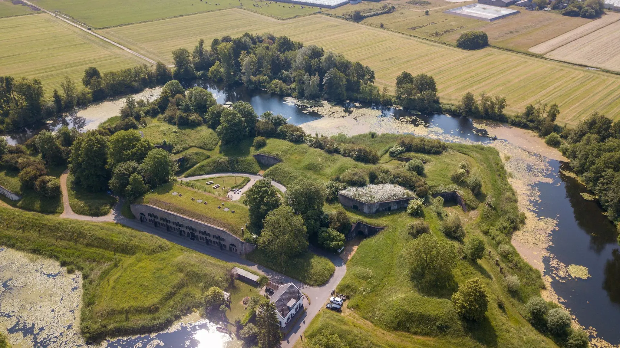 Luchtfoto van Fort aan de Fortweg, omringd door water, grasvelden en bomen in een landelijk landschap.