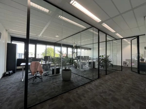 Moderne kantoorruimte aan de Wattbaan met glazen wanden, bureaus en kantoorplanten.