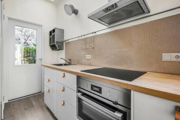 Moderne, smalle keuken aan de Westerstraat met houten aanrechtblad, inductiekookplaat en strakke afwerking.