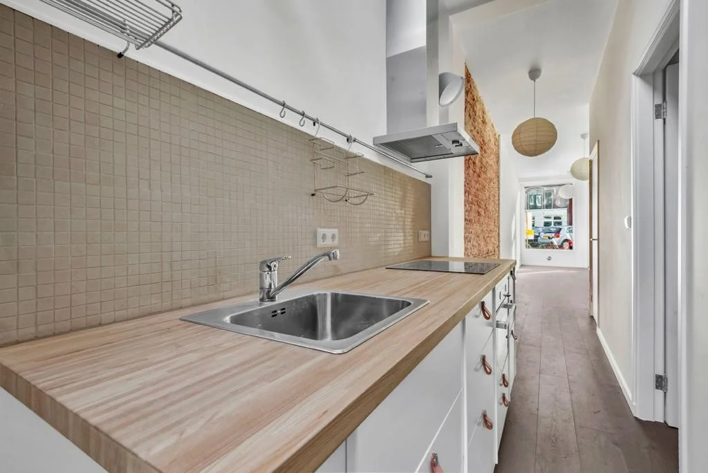 Smalle keuken met houten aanrechtblad, ingebouwde kookplaat en spoelbak aan de Westerstraat.
