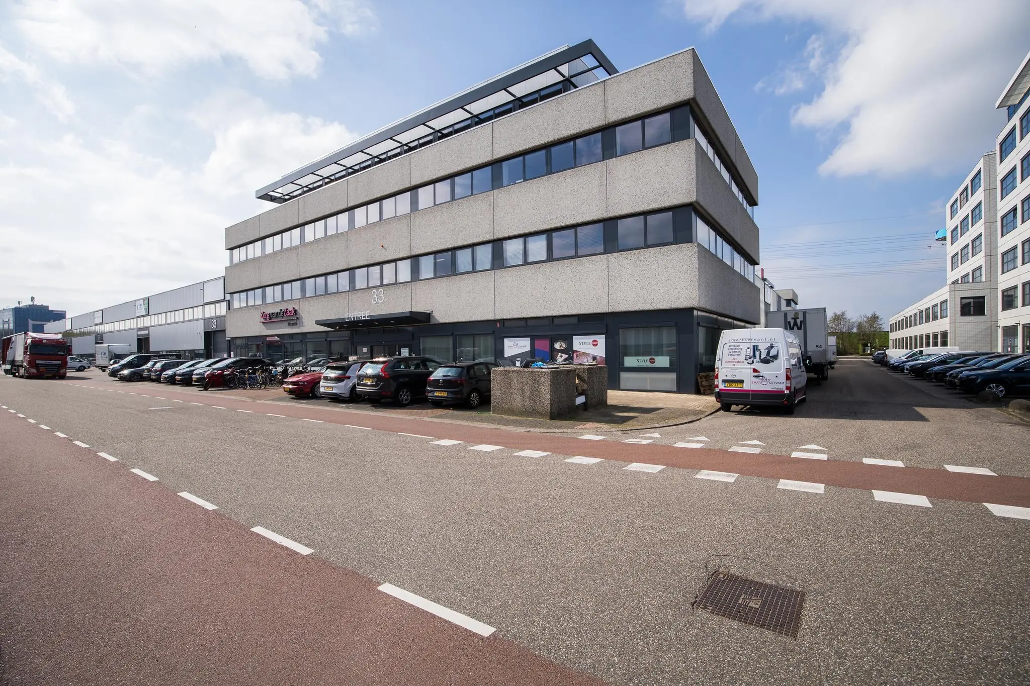 Bedrijventerrein met kantoorgebouw aan de Zonnebaan 33 in Utrecht, met geparkeerde auto’s en bestelwagens.