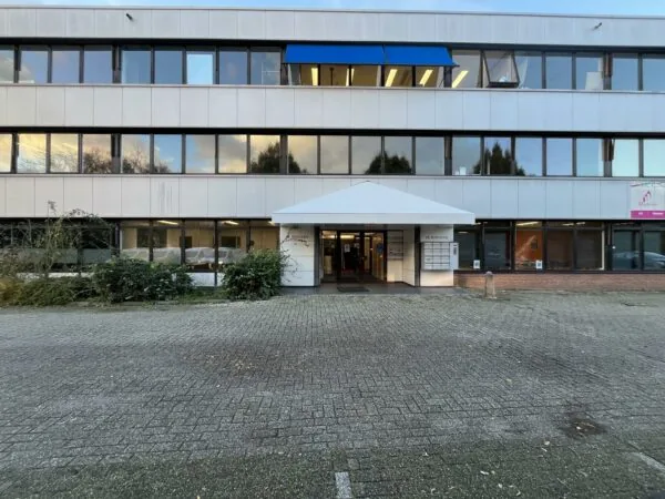Vooraanzicht van een kantoorpand aan de Industrieweg met ingang onder een witte overkapping.