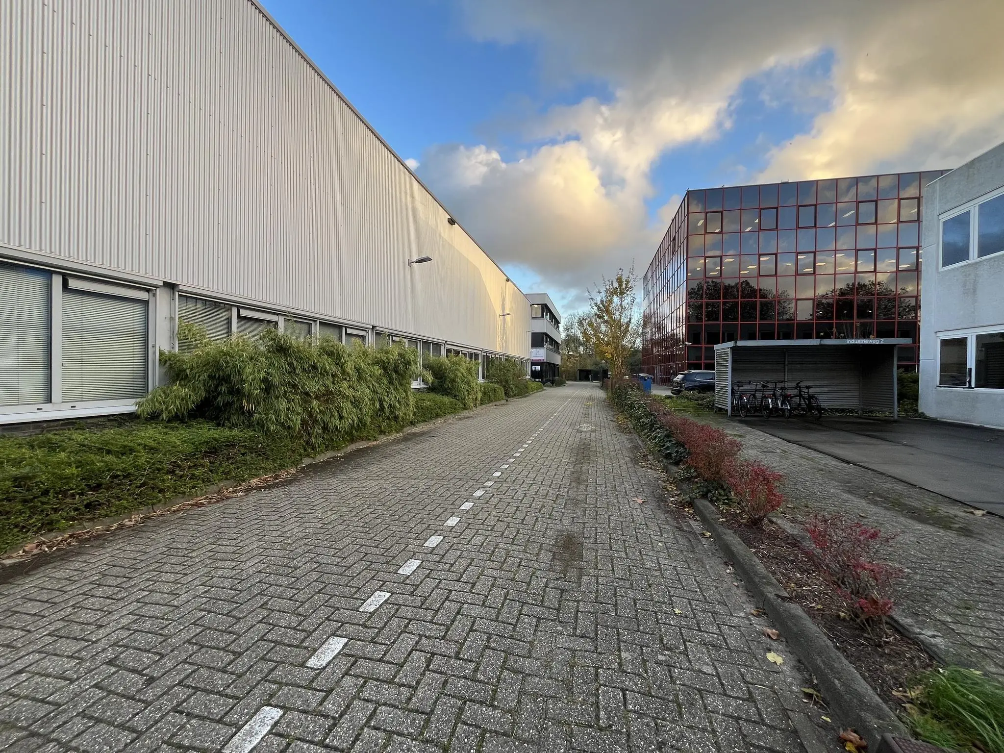 Bedrijventerrein aan de Industrieweg met kantoor- en bedrijfsgebouwen langs een betegeld pad bij zonsondergang.