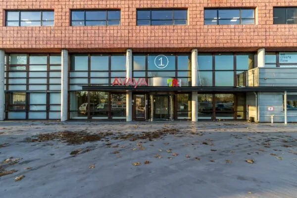 Vooraanzicht van een kantoorgebouw aan de Marconibaan met de bedrijfsnamen Avaya en DAH boven de ingang.