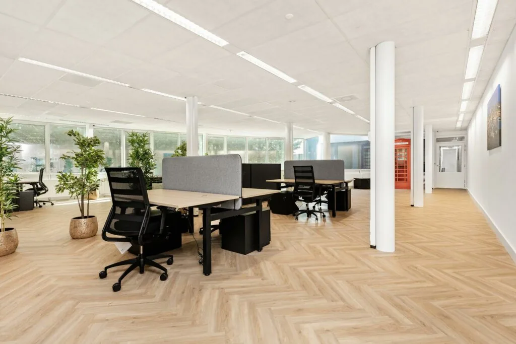 Modern en licht kantoorpand aan de Sluisjesdijk met flexwerkplekken, planten en een opvallende rode telefooncel.