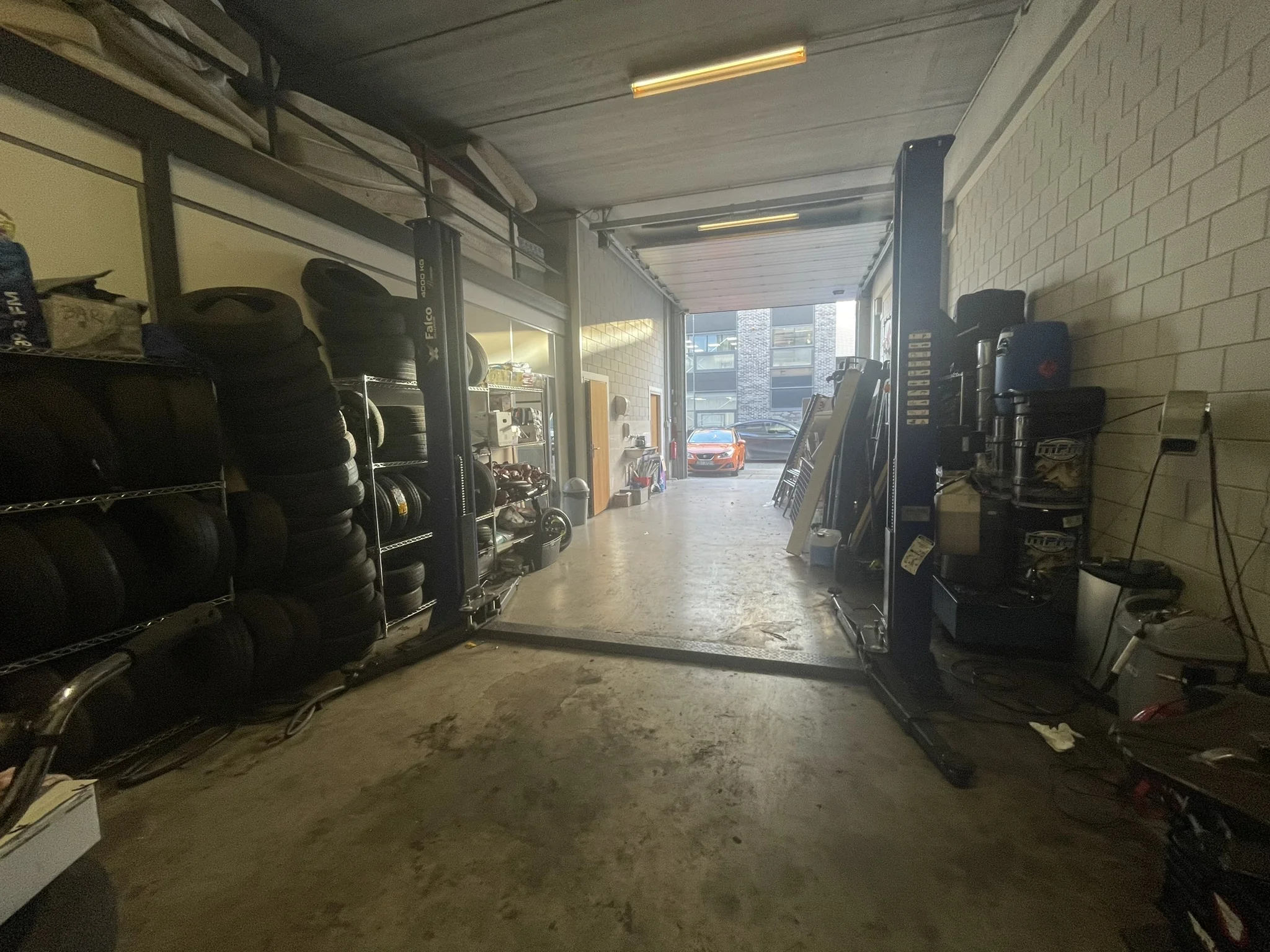 Garage met een lift en auto's op de achtergrond