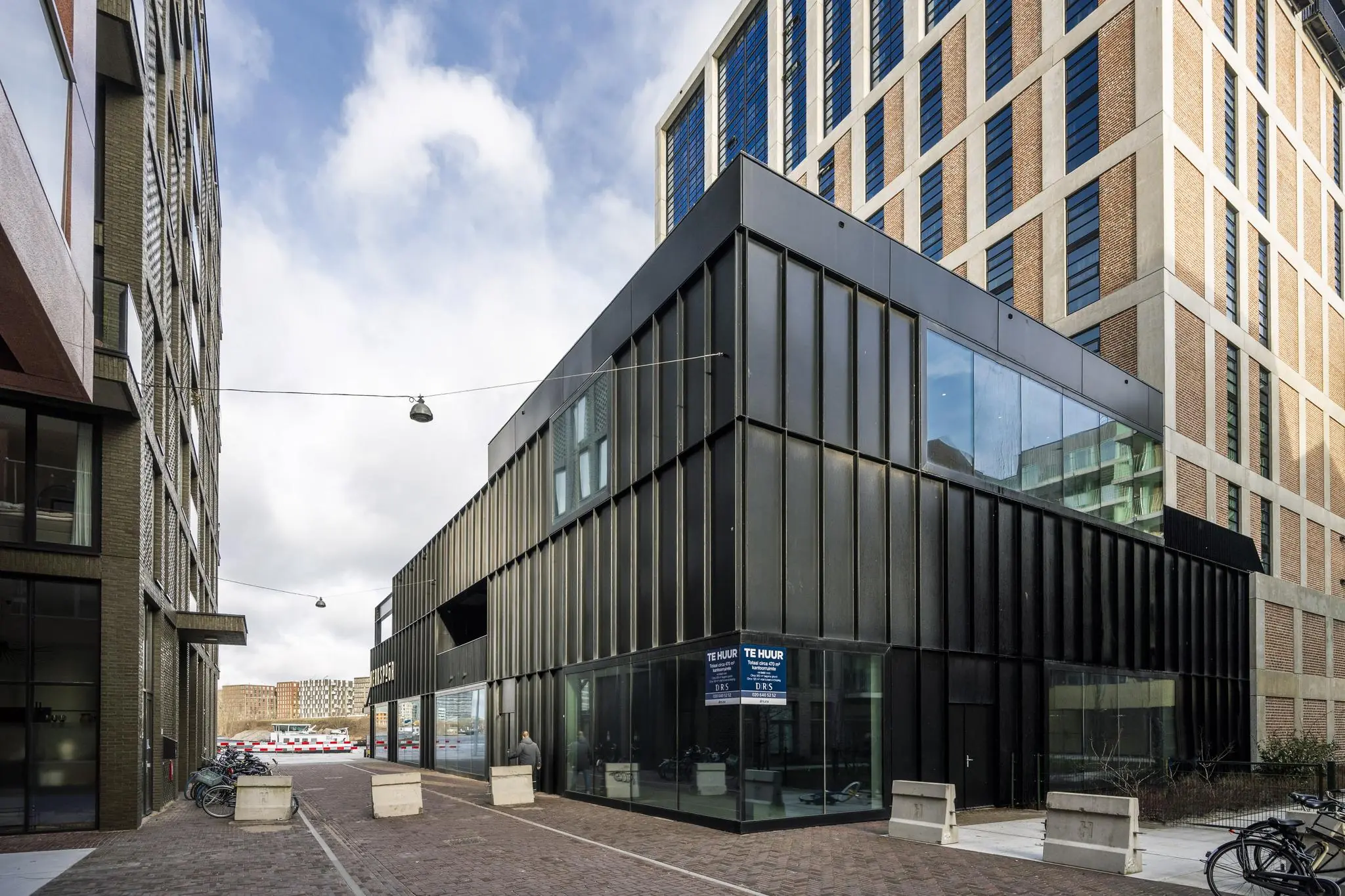 Moderne zwarte bedrijfsruimte te huur aan de Pieter Goosstraat, omgeven door hoge woongebouwen.
