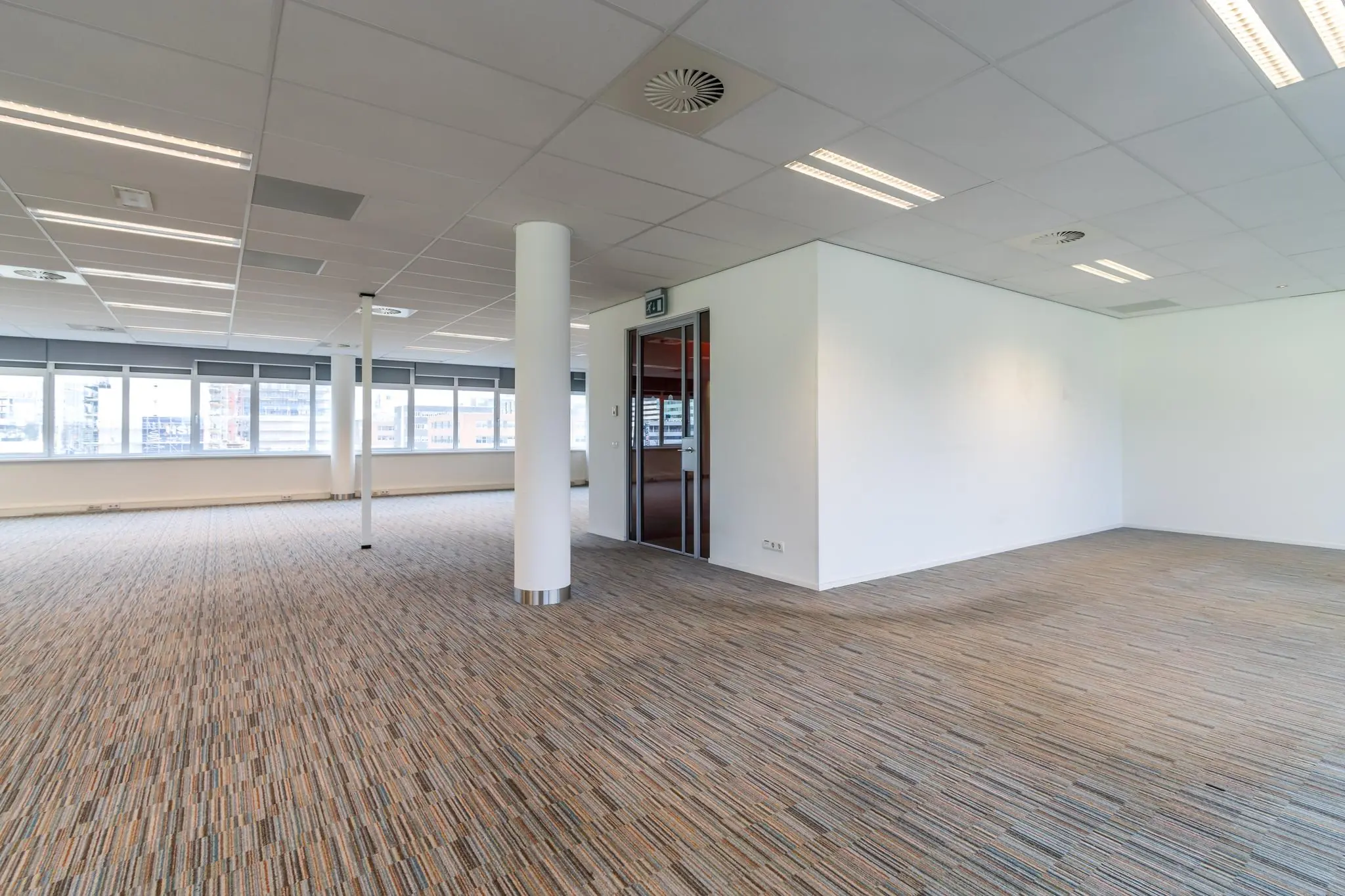 Licht en ruim kantoorinterieur aan de Lemelerbergweg met tapijtvloer, systeemplafond en grote ramen.