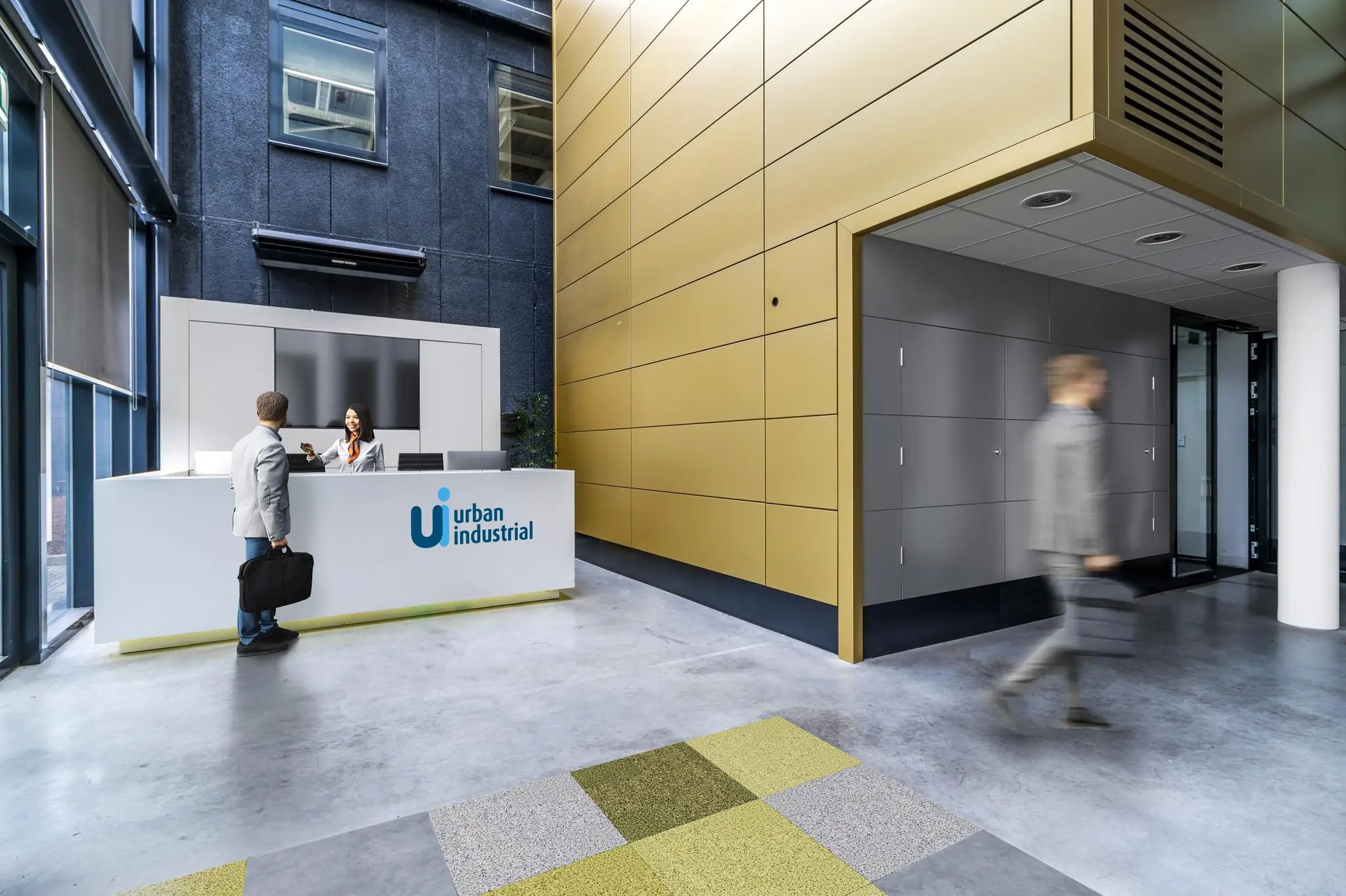 Moderne ontvangstbalie van Urban Industrial aan de Laarderhoogtweg met een receptionist die een bezoeker helpt.
