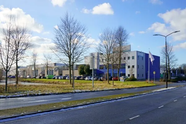 Bedrijventerrein aan de Zuiderweg met moderne kantoorgebouwen, geparkeerde auto's en een lege vlaggenmast op een zonnige winterdag.