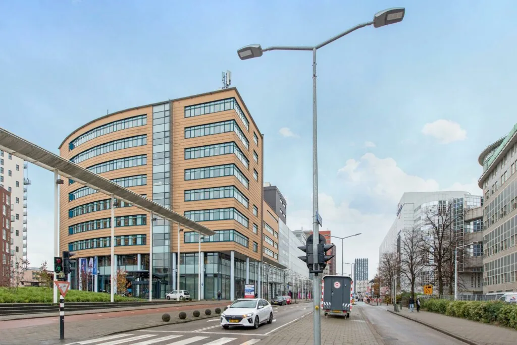 Straatbeeld van het Enthovenplein in Den Haag met moderne kantoorgebouwen en verkeer op de voorgrond.