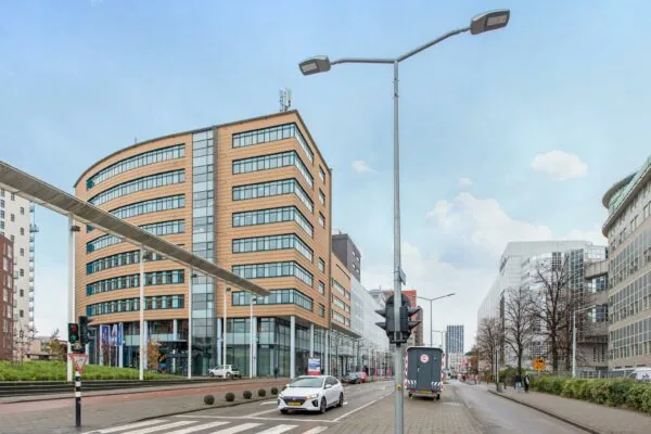 Straatbeeld van het Enthovenplein in Den Haag met moderne kantoorgebouwen en verkeer op de voorgrond.