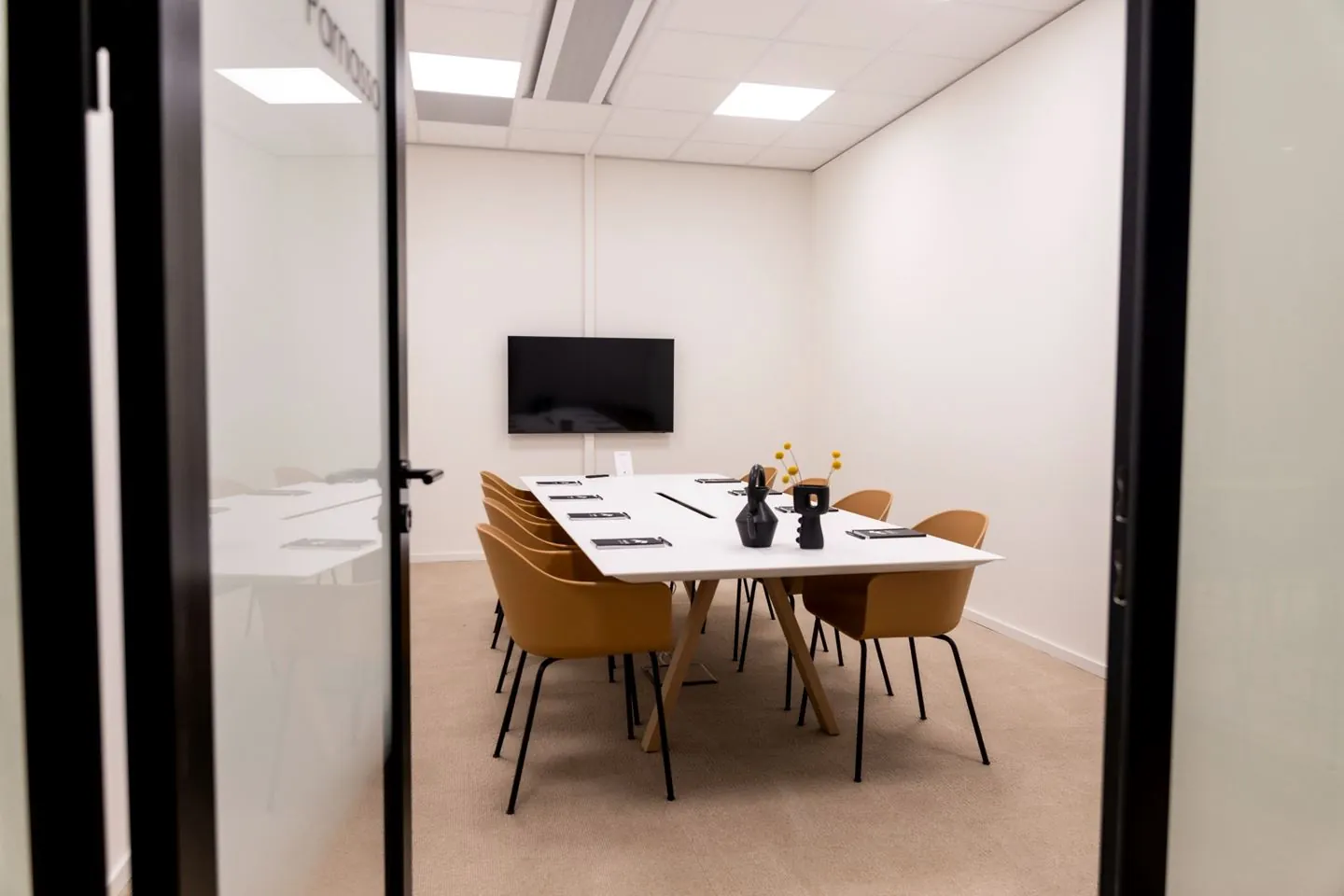 Vergaderruimte Rijnzathe met een lange tafel, acht stoelen, een flatscreen en moderne decoratie.