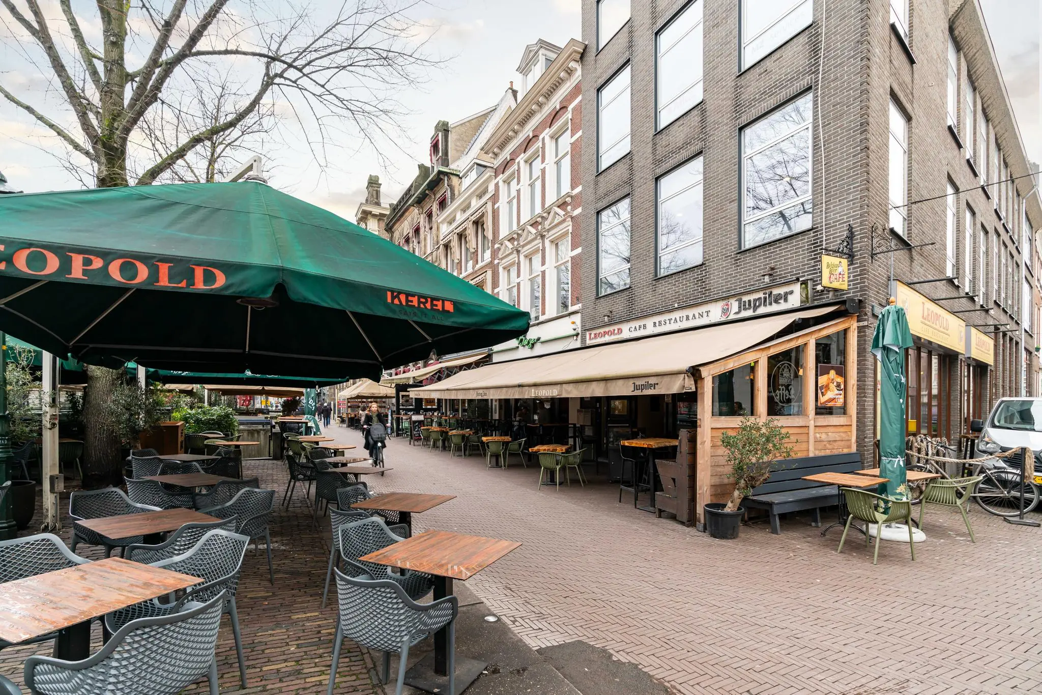 Terras en gevel van café-restaurant Leopold aan een gezellig plein met meerdere horecazaken.