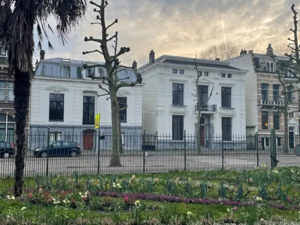 Witte herenhuizen aan de Plantage Middenlaan in Amsterdam met bloeiende voorjaarsbloemen op de voorgrond.