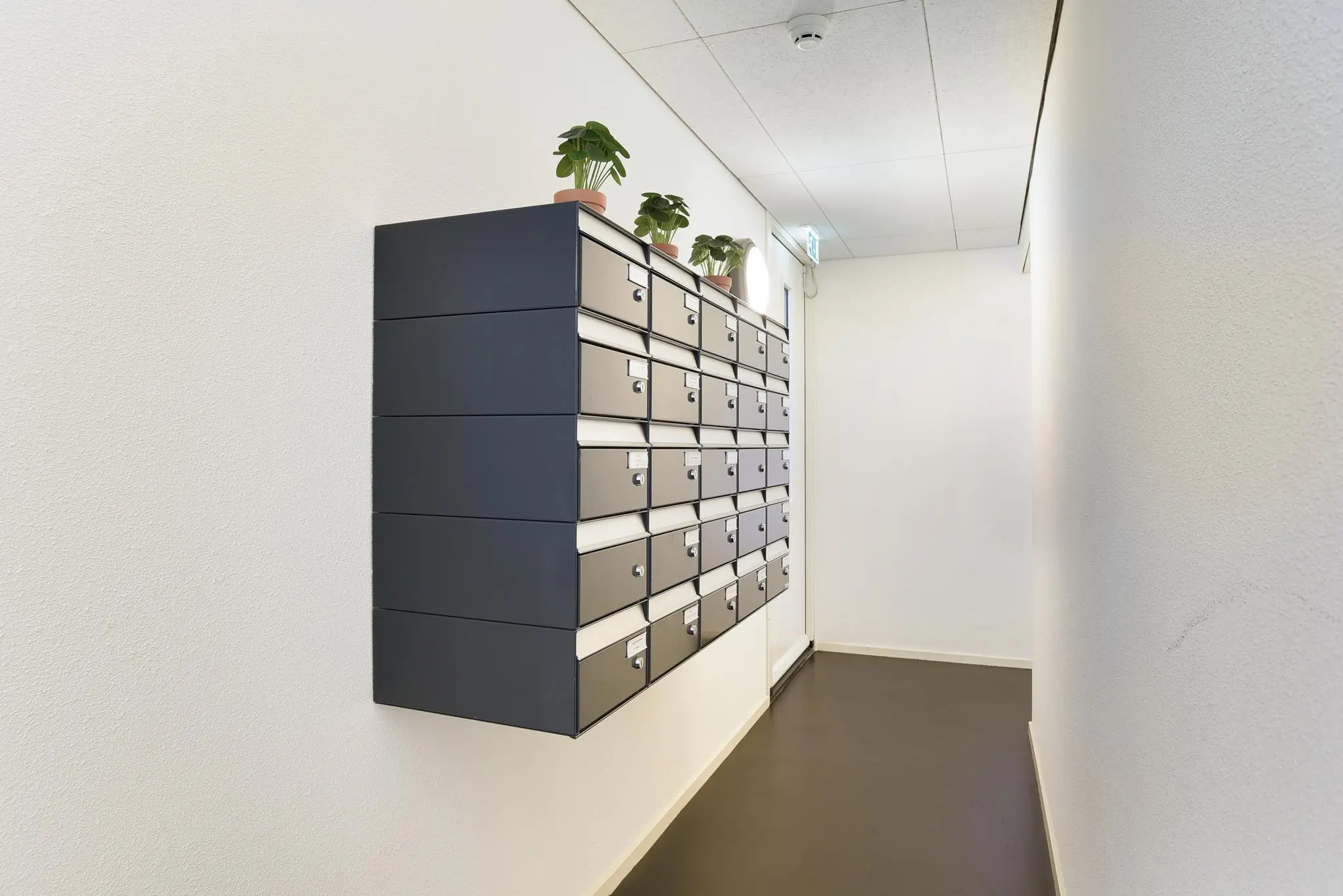 Wand met metalen brievenbussen in een lichte gang van het appartementencomplex Middenburcht.