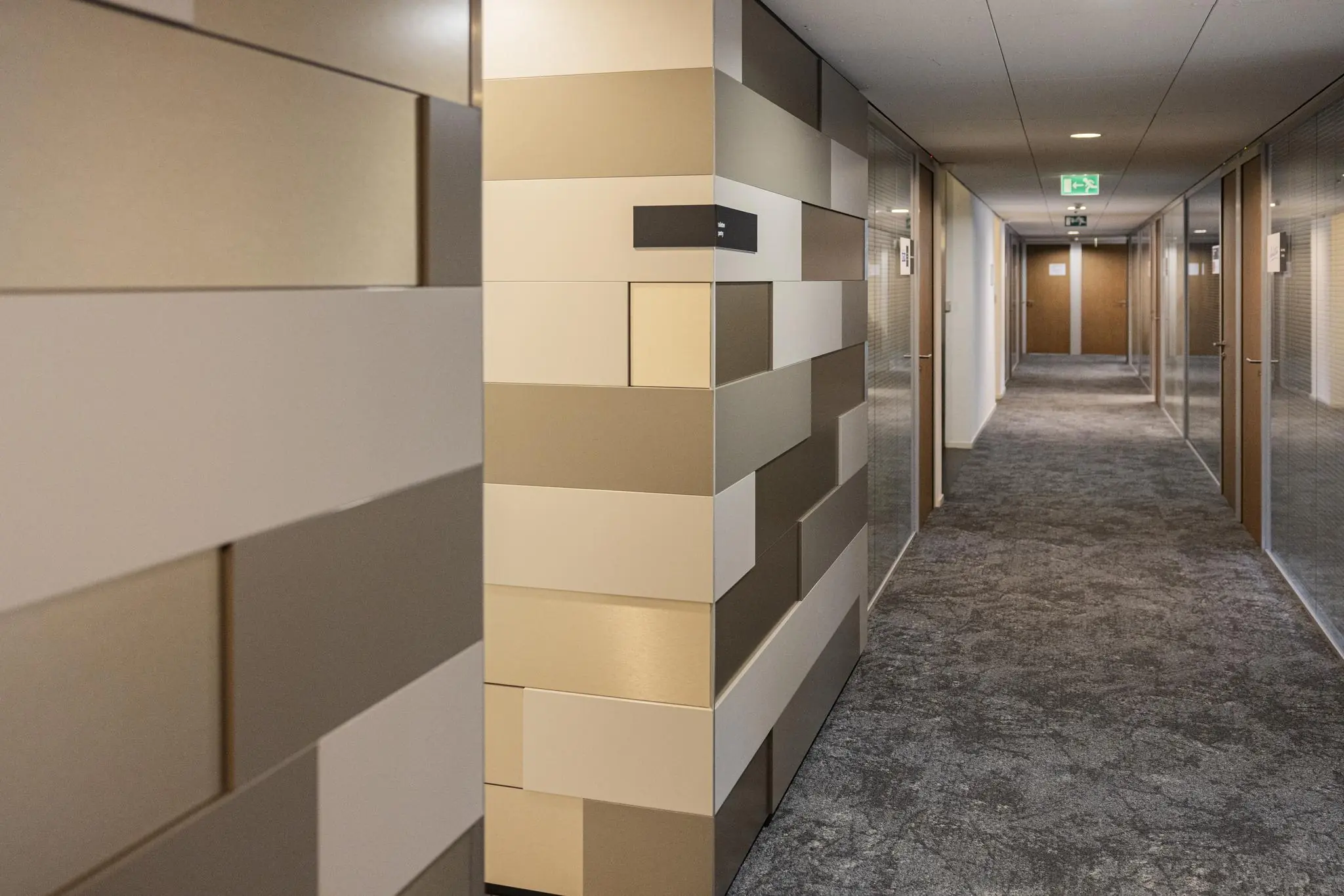 Moderne gang in kantoorpand Middenburcht met gekleurde wandpanelen en glazen kantoordeuren.