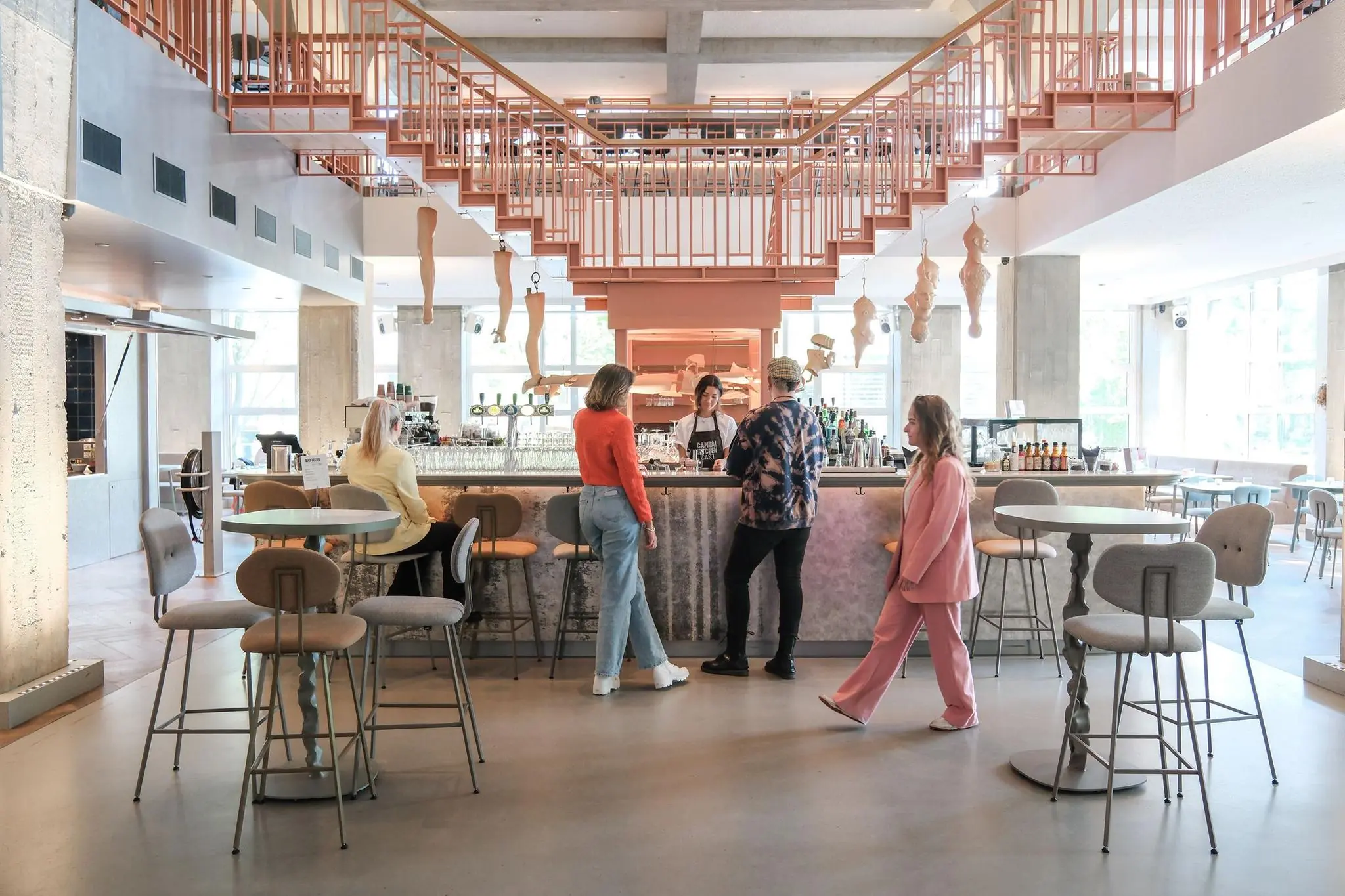 Modern café aan het Weesperplein met opvallend roze trapdesign en gasten aan de bar.