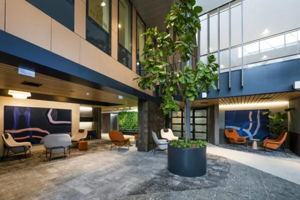 Moderne wachtruimte in een kantoor aan de Jachthavenweg, met designstoelen, kunst aan de muur en een grote binnentuinplant.