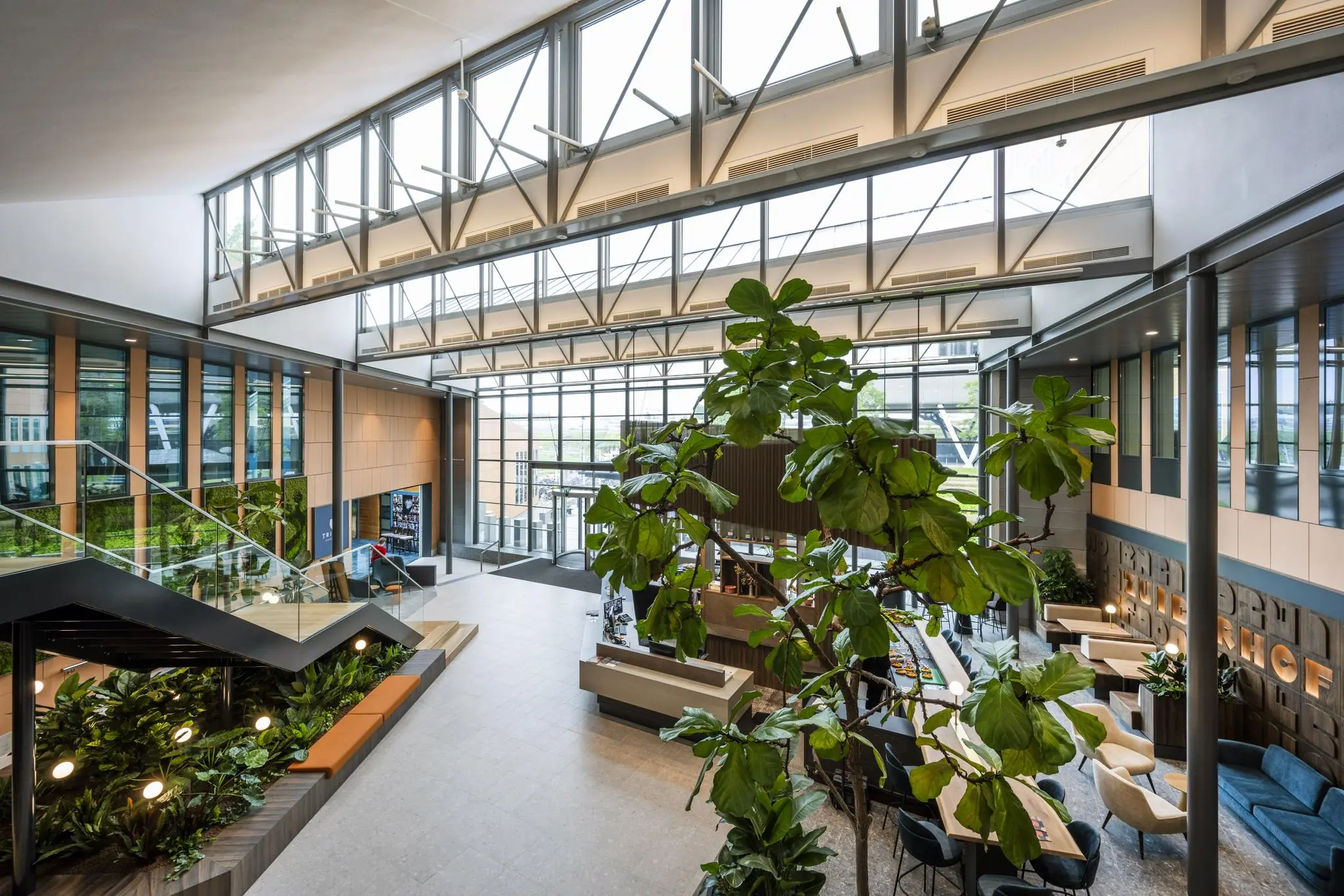 Moderne, lichtovergoten lobby aan de Jachthavenweg met glazen gevel, grote planten en zithoeken.