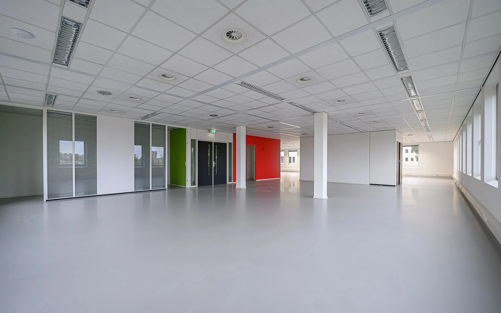 Leeg kantoorpand aan de Rivium 1e Straat met strakke afwerking, glazen wanden en kleuraccenten.