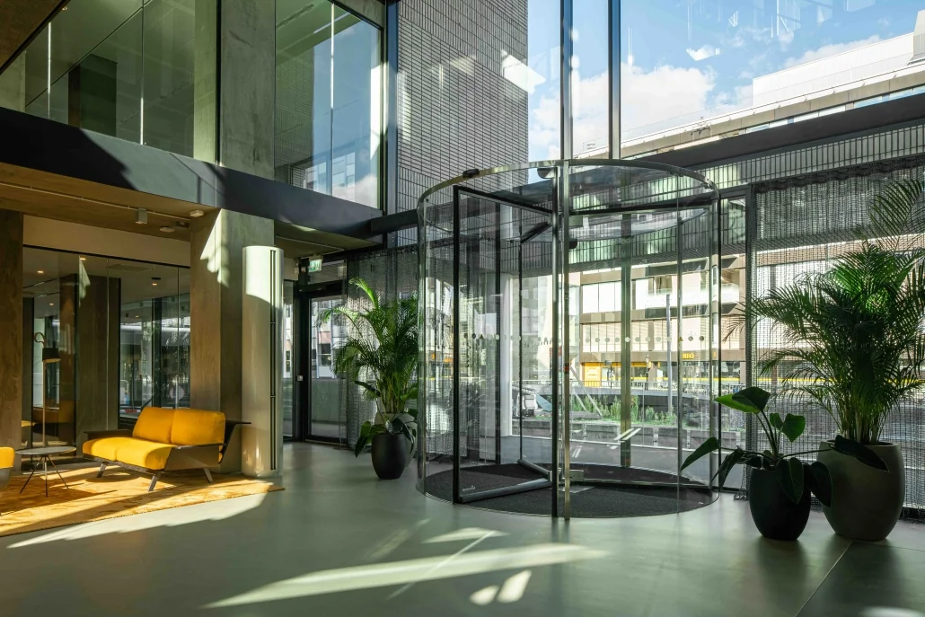Moderne entreehal van een kantoorgebouw aan de Catharijnesingel met glazen draaideur, gele zitbanken en veel daglicht.