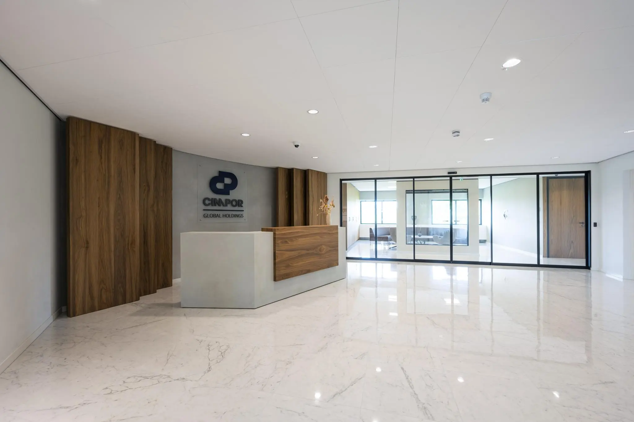 Moderne ontvangsthal van Cimpor Global Holdings met een strakke balie en glazen vergaderruimtes.