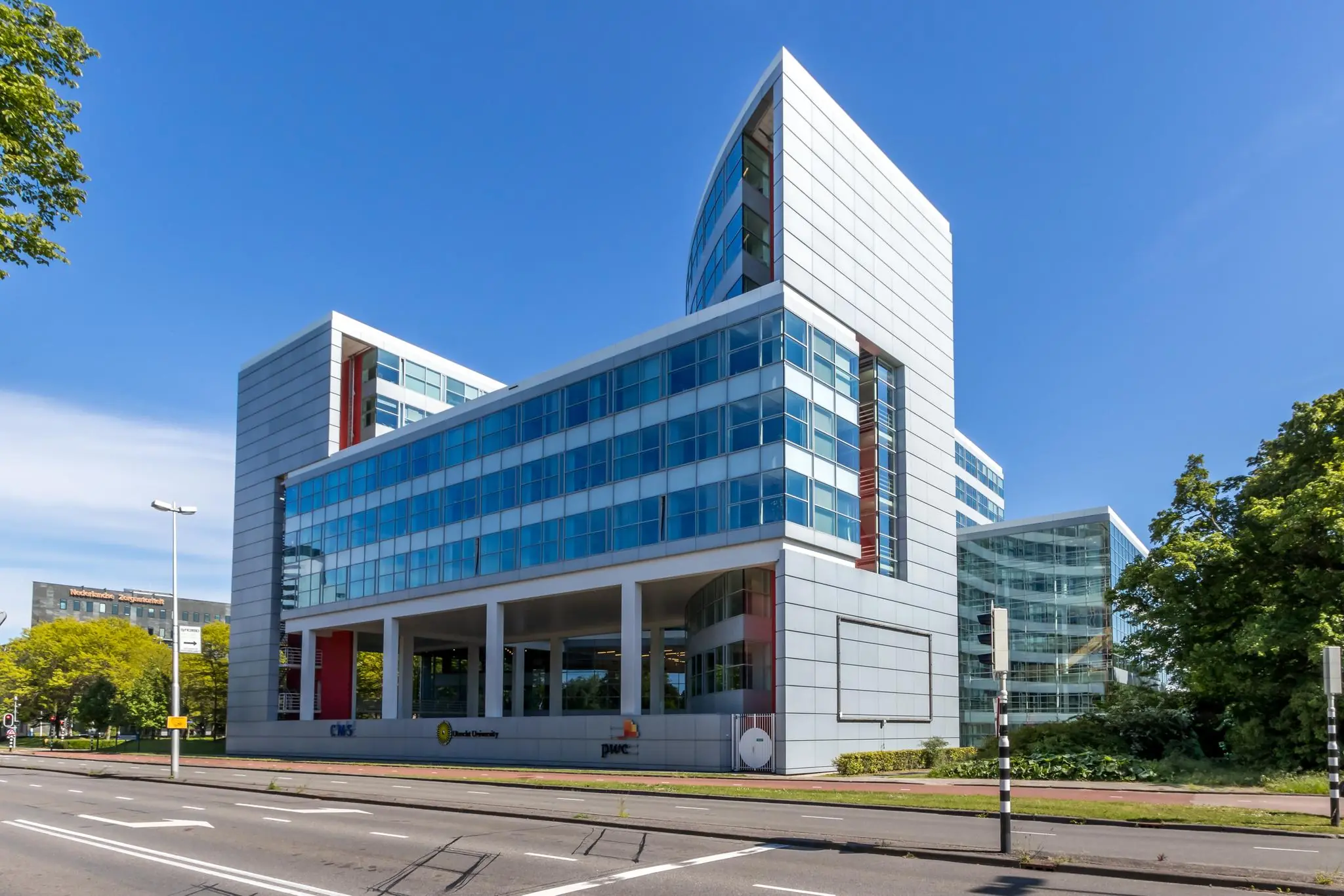 Modern kantoorgebouw aan de Newtonlaan in Utrecht met glazen gevels en prominente bedrijfslogo’s van o.a. PwC en Tio University.