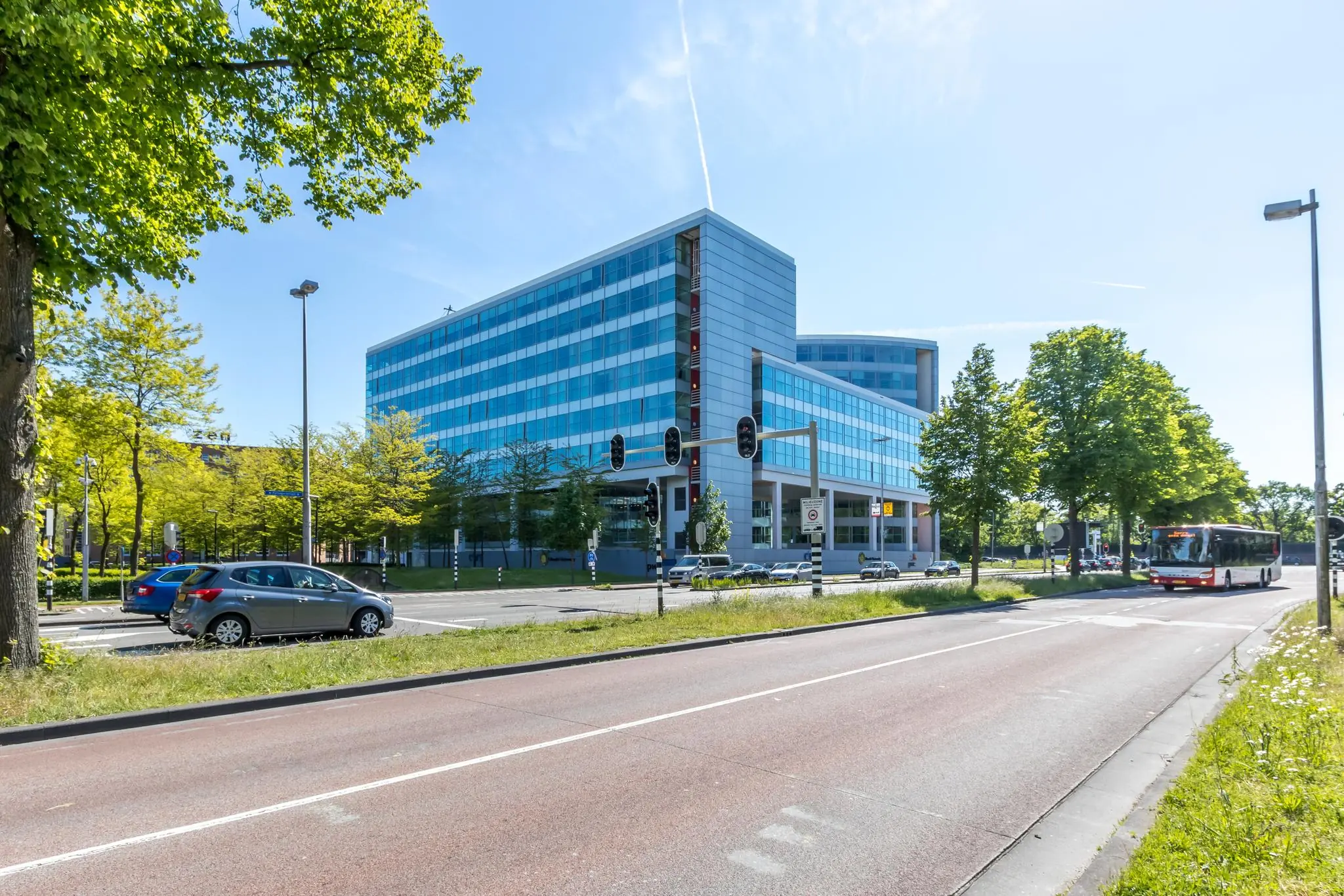 Modern kantoorgebouw aan de Newtonlaan in Utrecht, omringd door verkeer en groen.