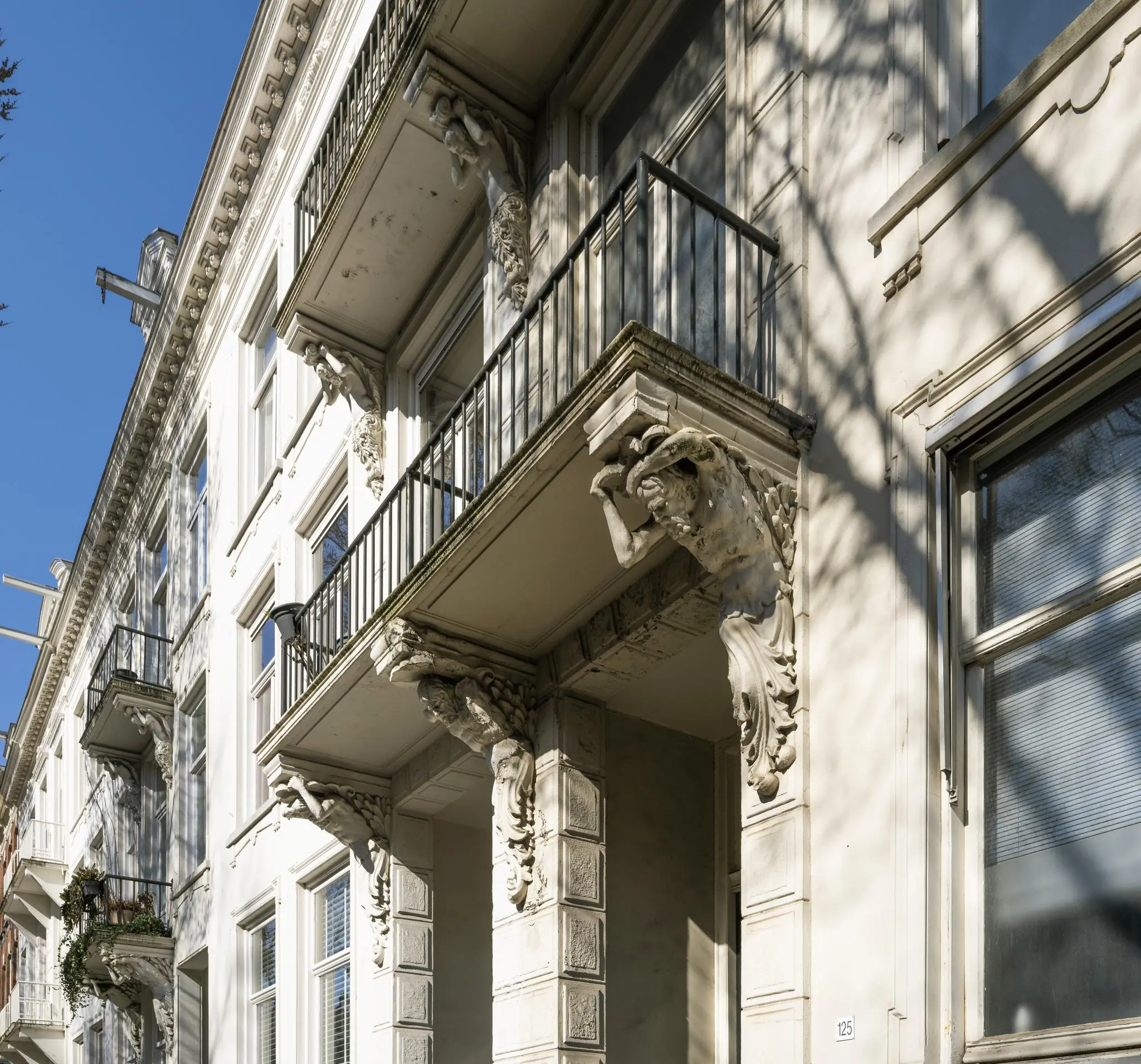 Voorgevel van een klassiek herenhuis aan de Sarphatistraat met rijk gedecoreerde balkons en beeldhouwwerken.