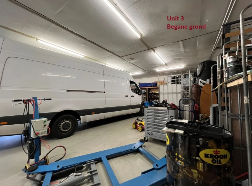Witte bestelbus in een werkplaats met gereedschap, olie en onderdelen, gemarkeerd als "Unit 3 Begane grond".
