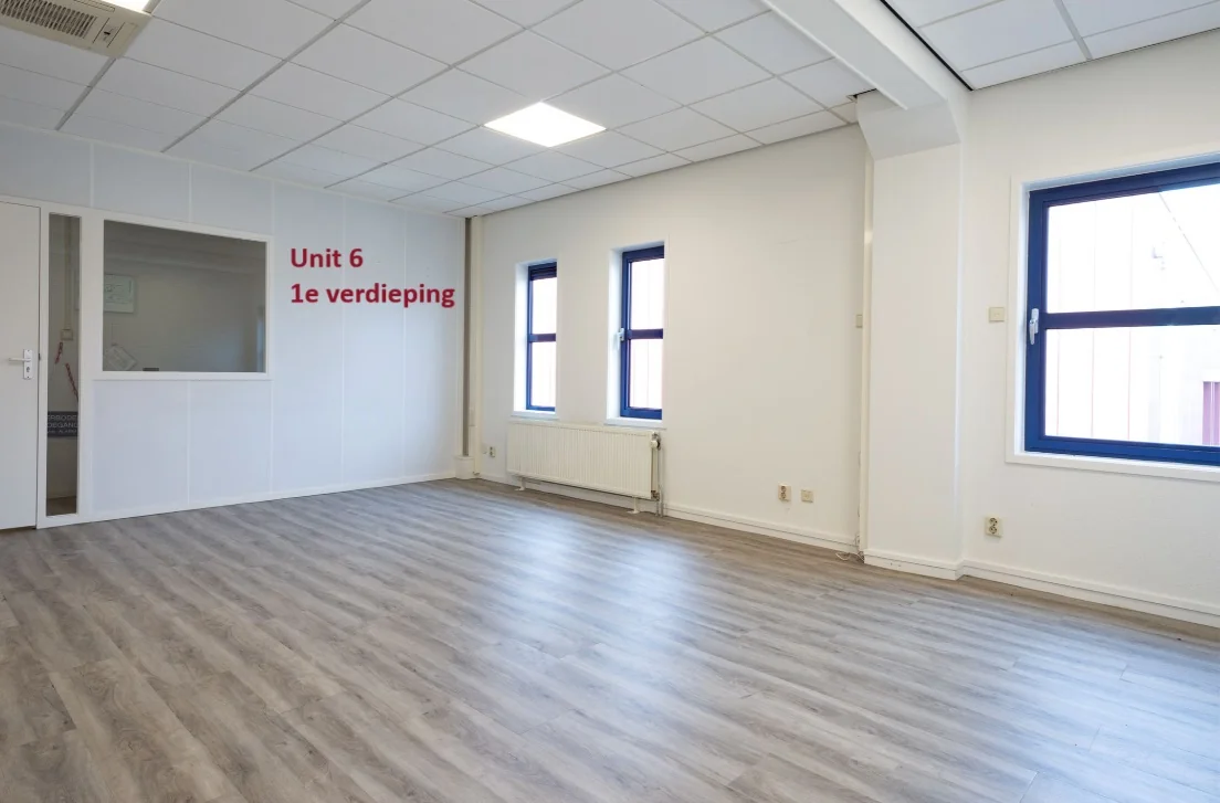 Lichte kantoorruimte met laminaatvloer en raamkozijnen, aangeduid als "Unit 6 1e verdieping".