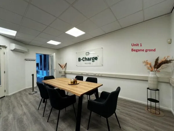 Vergaderruimte van B-Charge op de begane grond van Unit 1 met een houten tafel, zes zwarte stoelen en moderne inrichting.