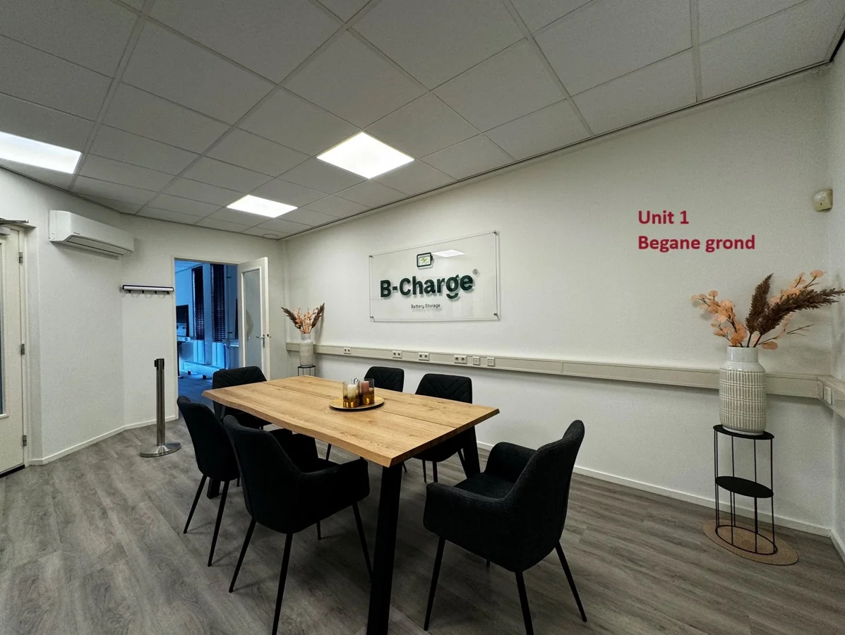 Vergaderruimte van B-Charge op de begane grond van Unit 1 met een houten tafel, zes zwarte stoelen en moderne inrichting.