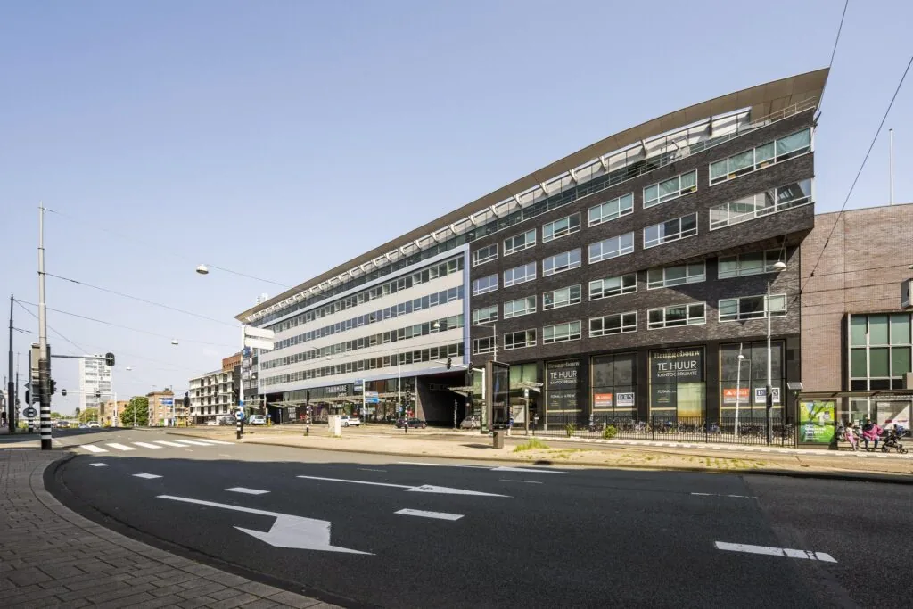 Modern kantoorgebouw aan het Bos en Lommerplein in Amsterdam met trambaan en bushalte op de voorgrond.