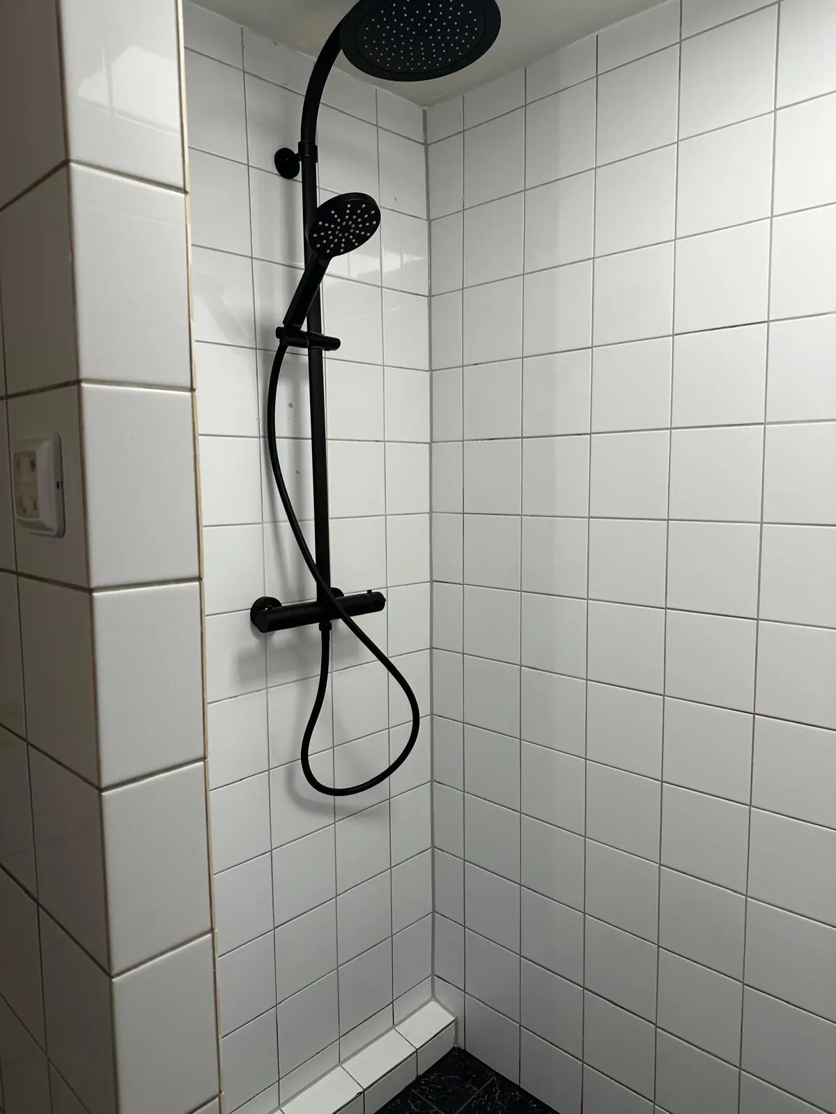 Moderne inloopdouche met witte tegels en een zwarte regendouche in een badkamer aan de Herengracht.