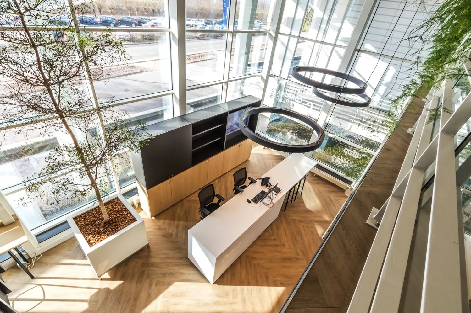 Moderne, lichte ontvangstruimte aan de Reactorweg met een balie, bureaustoelen, grote raampartijen en groene accenten.